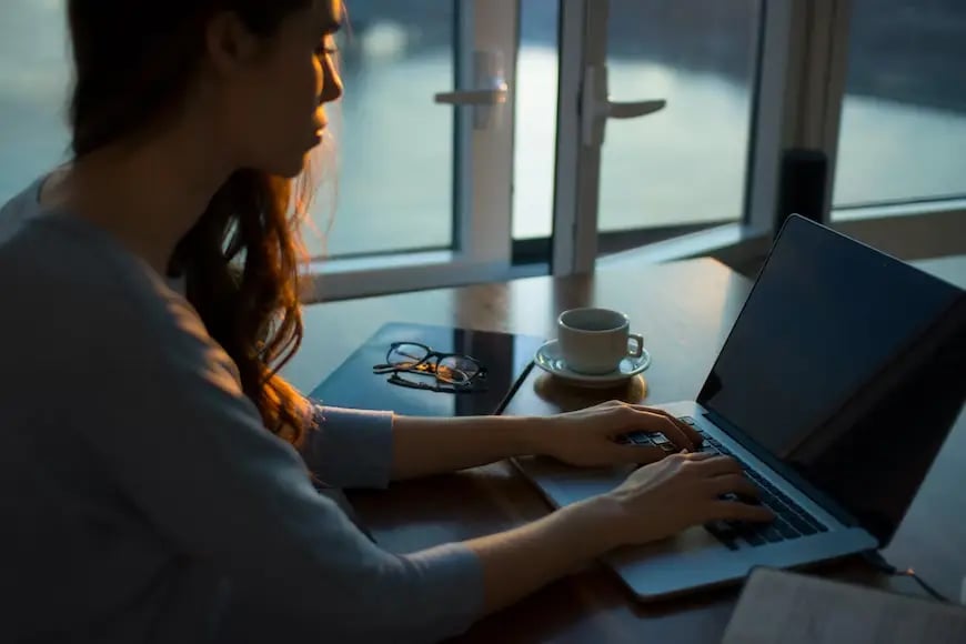 A person sitting at a desk typing on a laptop.